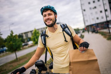 Şehir sokaklarında bisiklet süren kuryeler ellerinde yiyecek paketi, hızlı teslimat kavramı, şehir ulaşımı, kuryelik işi, modern şehir yaşam tarzı.