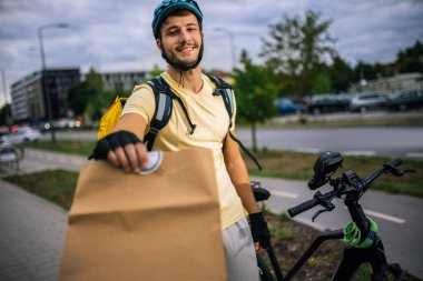 Kurye, dışarıdan gelen müşterilere yemek paketi sunuyor. Hızlı dağıtım konsepti, şehir hizmeti, modern şehir yaşam tarzı, kuryelik işi..