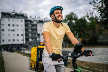 Bisikletli kurye şehir sokaklarında geziyor, sırt çantası taşıyor, fast food teslimatı konsepti, şehir ulaşımı, kuryelik işi, modern şehir yaşam tarzı.