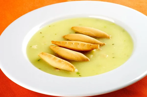 オレンジのナプキンにクローズ アップをパン棒と白プレートでおいしいクリーム アスパラガス スープ — ストック写真