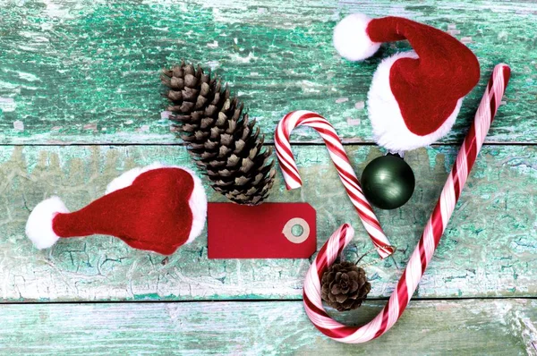 ひびの入った素朴な緑の背景にストライプの甘い杖 Fir コーン 小さなサンタ帽子 グリーティング カードのクローズ アップとクリスマスの装飾の概念 — ストック写真