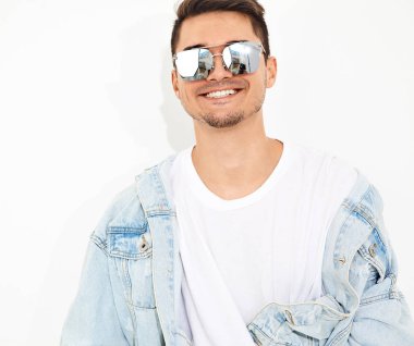 Yakışıklı gülümseyen genç model adam portresi beyaz arka plan üzerinde poz güneş gözlüğü kot elbise giymiş. İzole