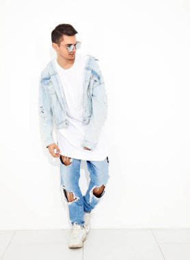 Yakışıklı genç model adam portresi beyaz arka plan üzerinde poz güneş gözlüğü kot elbise giymiş. İzole