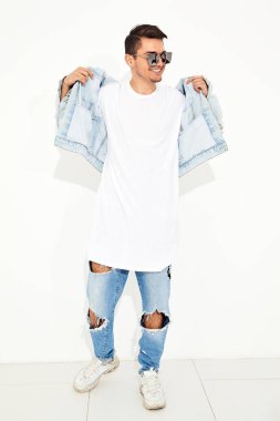 Yakışıklı gülümseyen genç model adam portresi beyaz arka plan üzerinde poz güneş gözlüğü kot elbise giymiş. İzole
