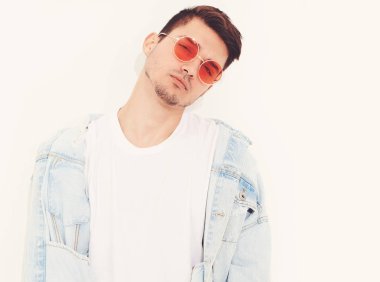 Yakışıklı genç model adam portresi beyaz arka plan üzerinde poz güneş gözlüğü kot elbise giymiş. İzole