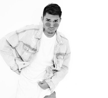 Yakışıklı genç model adam portresi beyaz arka plan üzerinde poz güneş gözlüğü kot elbise giymiş. İzole