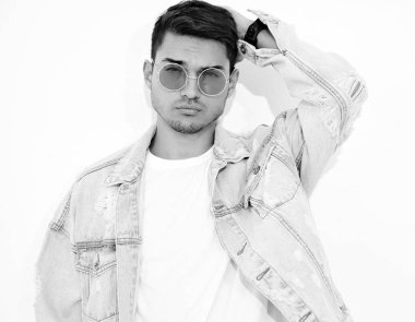 Yakışıklı genç model adam portresi beyaz arka plan üzerinde poz güneş gözlüğü kot elbise giymiş. İzole