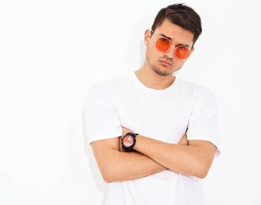 Yakışıklı genç model adam portresi beyaz arka plan üzerinde poz güneş gözlüğü kot elbise ve T-shirt giymiş. Çapraz kollar