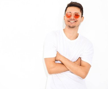 Yakışıklı genç model adam portresi beyaz arka plan üzerinde poz güneş gözlüğü kot elbise ve T-shirt giymiş. Çapraz kollar