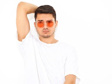 Yakışıklı genç model adam portresi beyaz arka plan üzerinde poz güneş gözlüğü kot elbise ve T-shirt giymiş. Kafasını dokunmadan