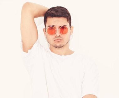 Yakışıklı genç model adam portresi beyaz arka plan üzerinde poz güneş gözlüğü kot elbise ve T-shirt giymiş. Kafasını dokunmadan