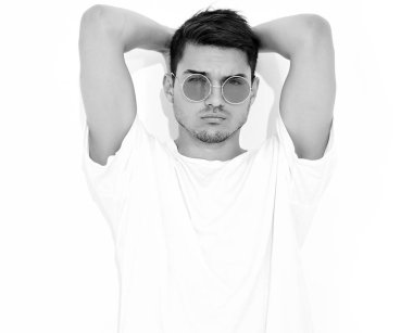 Yakışıklı genç model adam portresi beyaz arka plan üzerinde poz güneş gözlüğü kot elbise ve T-shirt giymiş. Kafasını dokunmadan