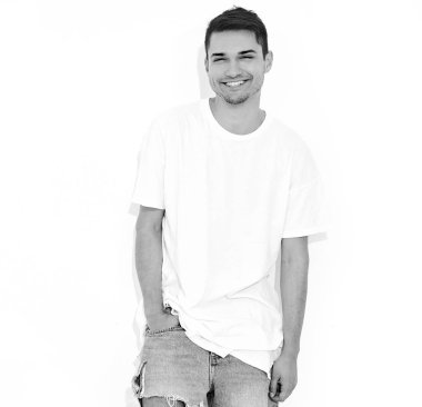 Yakışıklı gülümseyen genç model adam portresi kot elbise ve T-shirt beyaz arka plan üzerinde poz giyinmiş. Kafasını dokunmadan