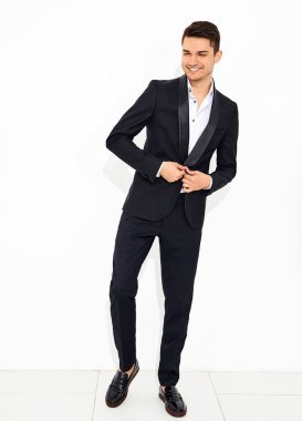 yakışıklı gülümseyen şık hipster lumbersexual işadamı modeli portre Studio beyaz duvarının yakınında poz zarif siyah klasik takım elbise giymiş. Metroseksüel