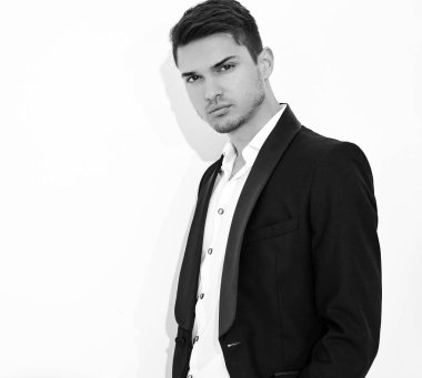 yakışıklı moda şık hipster lumbersexual işadamı modelinin portre Studio beyaz duvarının yakınında poz zarif siyah klasik takım elbise giymiş. Metroseksüel