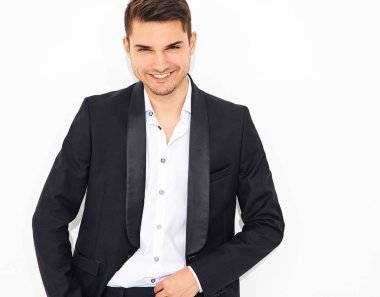 yakışıklı gülümseyen şık hipster lumbersexual işadamı modeli portre Studio beyaz duvarının yakınında poz zarif siyah klasik takım elbise giymiş. Metroseksüel