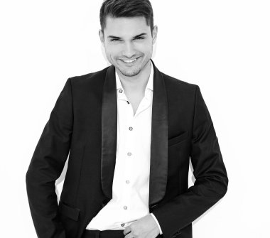 yakışıklı gülümseyen şık hipster lumbersexual işadamı modeli portre Studio beyaz duvarının yakınında poz zarif siyah klasik takım elbise giymiş. Metroseksüel