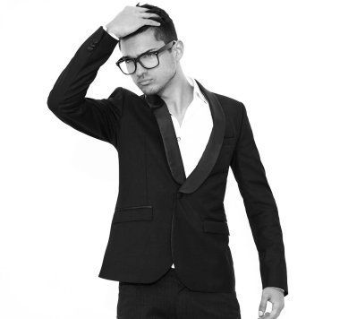 yakışıklı moda şık hipster lumbersexual işadamı modelinin portre Studio beyaz duvarının yakınında poz zarif siyah klasik takım elbise giymiş. Metroseksüel