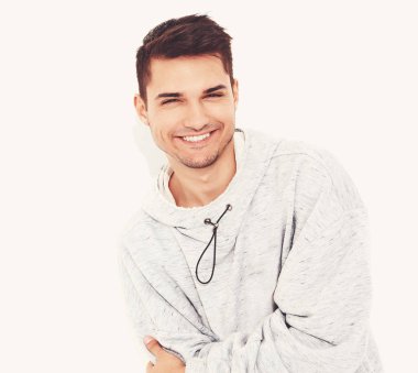 Yakışıklı model adam gülümseyen genç portresi beyaz arka plan üzerinde poz gri rahat Kapşonlu elbise giymiş. İzole