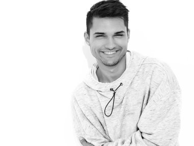 Yakışıklı model adam gülümseyen genç portresi beyaz arka plan üzerinde poz gri rahat Kapşonlu elbise giymiş. İzole