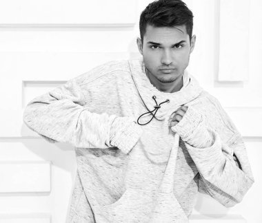Genç yakışıklı modeli adam portresi dokulu beyaz duvara yakın poz gri rahat Kapşonlu elbise giymiş