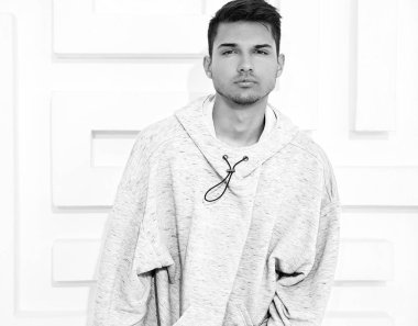 Genç yakışıklı modeli adam portresi dokulu beyaz duvara yakın poz gri rahat Kapşonlu elbise giymiş
