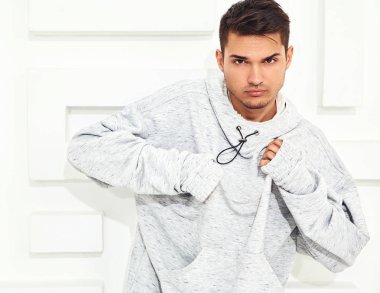 Genç yakışıklı modeli adam portresi dokulu beyaz duvara yakın poz gri rahat Kapşonlu elbise giymiş