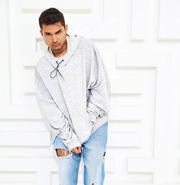 Genç yakışıklı modeli adam portresi dokulu beyaz duvara yakın poz gri rahat Kapşonlu elbise giymiş