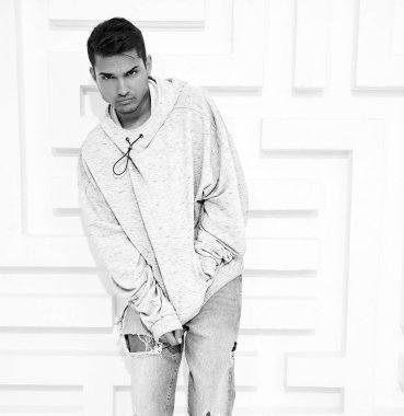 Genç yakışıklı modeli adam portresi dokulu beyaz duvara yakın poz gri rahat Kapşonlu elbise giymiş