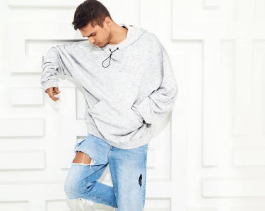 Genç yakışıklı modeli adam portresi dokulu beyaz duvara yakın poz gri rahat Kapşonlu elbise giymiş