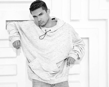Genç yakışıklı modeli adam portresi dokulu beyaz duvara yakın poz gri rahat Kapşonlu elbise giymiş