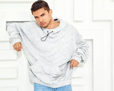 Genç yakışıklı modeli adam portresi dokulu beyaz duvara yakın poz gri rahat Kapşonlu elbise giymiş