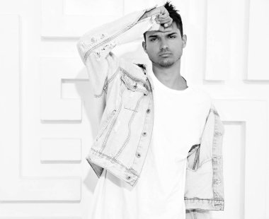 Genç yakışıklı modeli adam portresi dokulu beyaz duvara yakın poz gri rahat Kapşonlu elbise giymiş