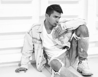 Yakışıklı genç model adam portresi beyaz dokulu duvara yakın oturan kot elbise giymiş