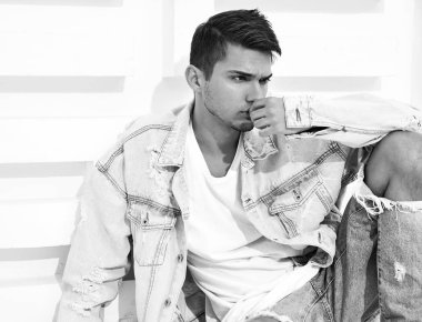Yakışıklı genç model adam portresi beyaz dokulu duvara yakın oturan kot elbise giymiş
