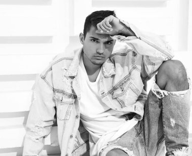 Yakışıklı genç model adam portresi beyaz dokulu duvara yakın oturan kot elbise giymiş