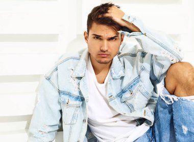 Yakışıklı genç model adam portresi beyaz dokulu duvara yakın oturan kot elbise giymiş