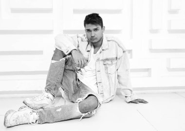 Yakışıklı genç model adam portresi beyaz dokulu duvara yakın oturan kot elbise giymiş