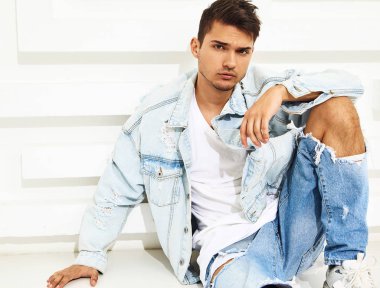 Yakışıklı genç model adam portresi beyaz dokulu duvara yakın oturan kot elbise giymiş