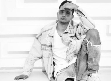 Yakışıklı genç model adam portresi beyaz dokulu duvara yakın oturan kot elbise giymiş