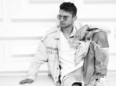 Yakışıklı genç model adam portresi beyaz dokulu duvara yakın oturan kot elbise giymiş