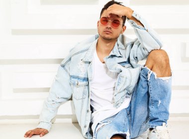 Yakışıklı genç model adam portresi beyaz dokulu duvara yakın oturan kot elbise giymiş