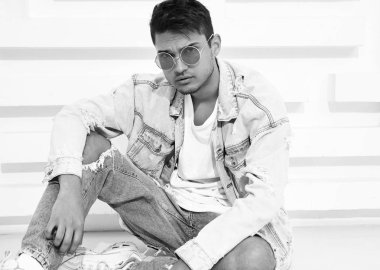 Yakışıklı genç model adam portresi beyaz dokulu duvara yakın oturan kot elbise giymiş