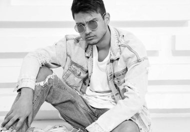 Yakışıklı genç model adam portresi beyaz dokulu duvara yakın oturan kot elbise giymiş