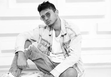 Yakışıklı genç model adam portresi beyaz dokulu duvara yakın oturan kot elbise giymiş