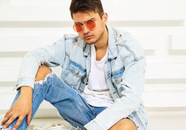Yakışıklı genç model adam portresi beyaz dokulu duvara yakın oturan kot elbise giymiş