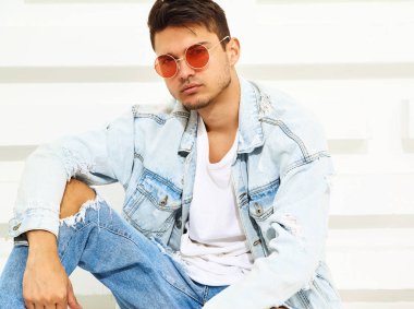 Yakışıklı genç model adam portresi beyaz dokulu duvara yakın oturan kot elbise giymiş