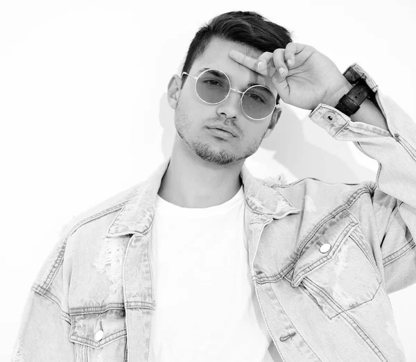 Yakışıklı genç model adam portresi beyaz arka plan üzerinde poz güneş gözlüğü kot elbise giymiş. İzole