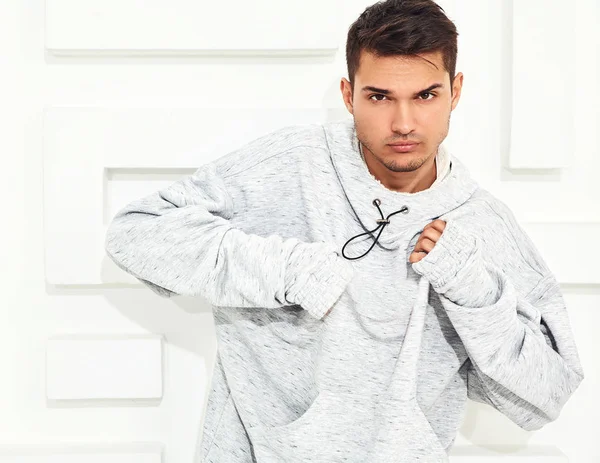 Genç yakışıklı modeli adam portresi dokulu beyaz duvara yakın poz gri rahat Kapşonlu elbise giymiş