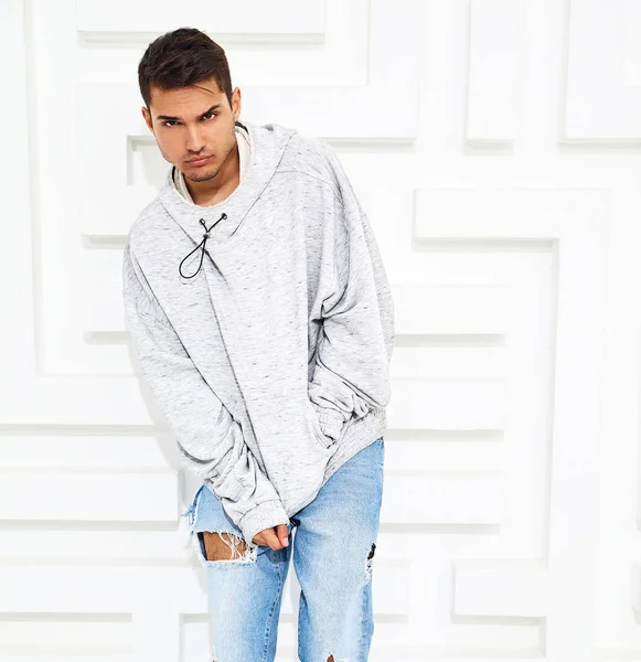 Genç yakışıklı modeli adam portresi dokulu beyaz duvara yakın poz gri rahat Kapşonlu elbise giymiş